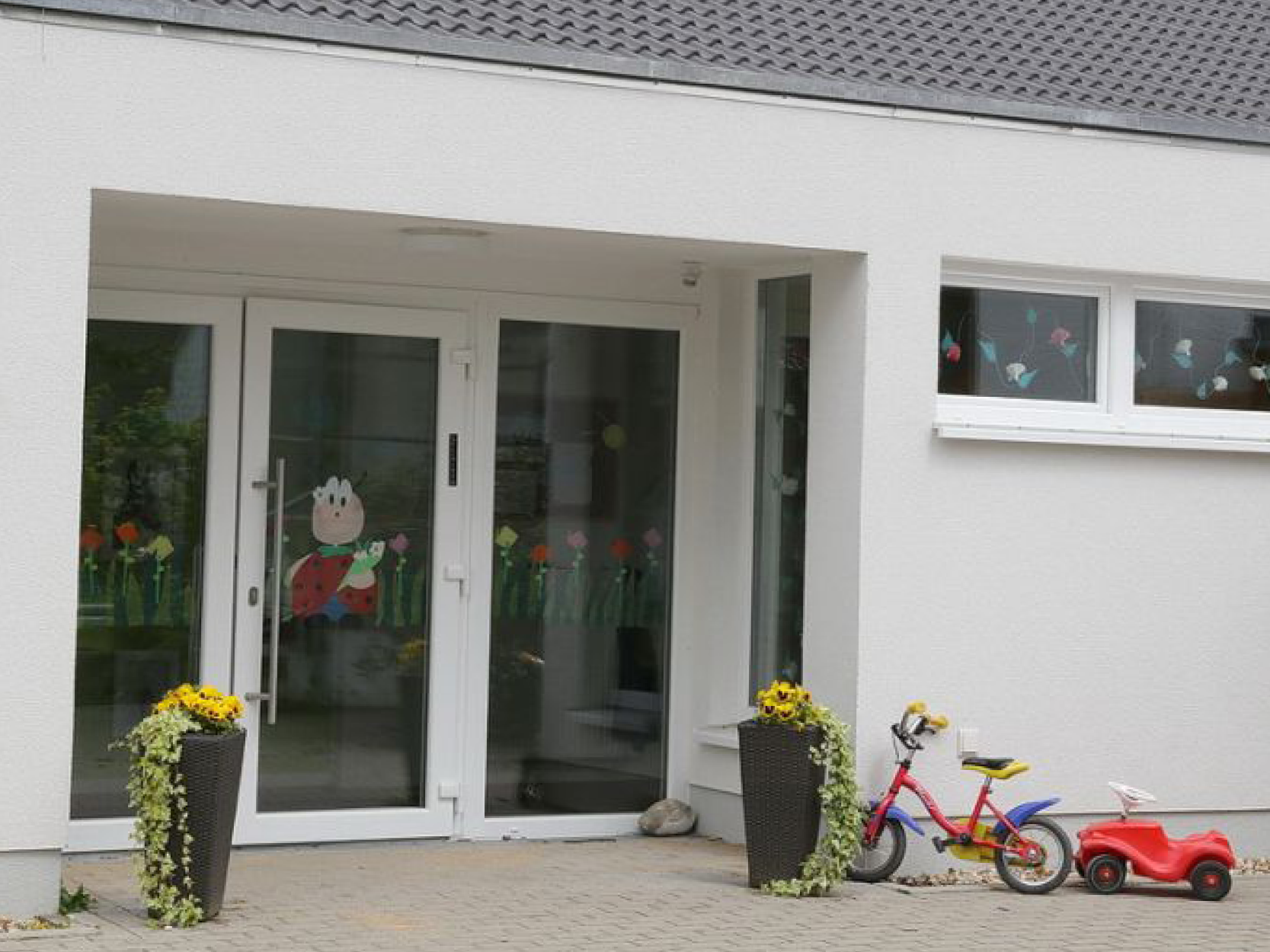 Die moderne Außenfassade des Kindergarten-Gebäudes in Loope mit großen Fenstern.